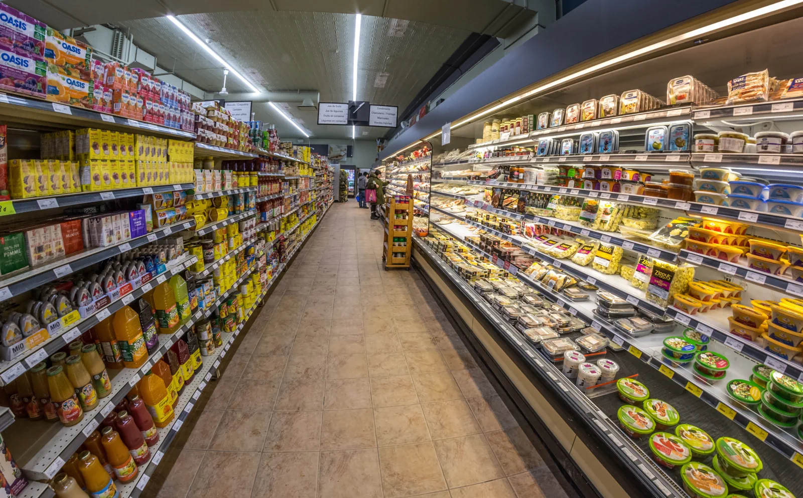 A long supermarket aisle with shelves and chilled cabinets on both sides, in Quebec City